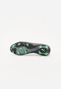 Sole di scarpa da calcio nera e verde con linee testurizzate, tacchetti circolari prominenti e logo Puma in bianco.