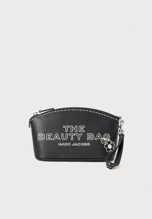 Geantă cosmetică din piele neagră, cu un capac curbat, inscripționată cu litere albe "THE BEAUTY BAG" și "MARC JACOBS", având un pandantiv în formă de floare și închidere tip fermoar.
