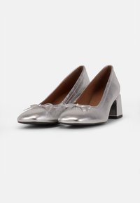 Scarpe col tacco alto metalliche argento con punta affusolata, dettaglio a fiocco sulla parte anteriore e tacco a blocco spesso. Texture liscia e finitura lucida.