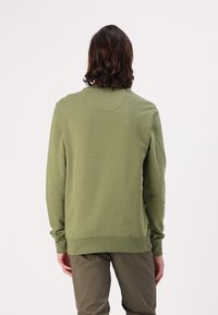 Zeleni pamučni dukserica s dugim rukavima i rebrastim manžetama. Glatka tekstura, okrugli izrez i suptilan logotip na rubu.