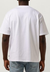 Vit bomull t-shirt med korta ärmar och rund halsringning, som har en avslappnad passform och slät textur. Baksidan visar inga tryck eller dekorationer.