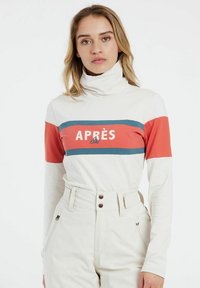 Langärmliger Rollkragenpullover in Weiß mit roten und türkisfarbenen horizontalen Streifen. Auf der Vorderseite steht der Text "APRÈS Ski" in Weiß.