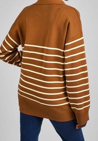 Maglione marrone con righe orizzontali color crema, dotato di collo a camicia, vestibilità ampia e orlo a costine. Realizzato in tessuto a maglia strutturato.