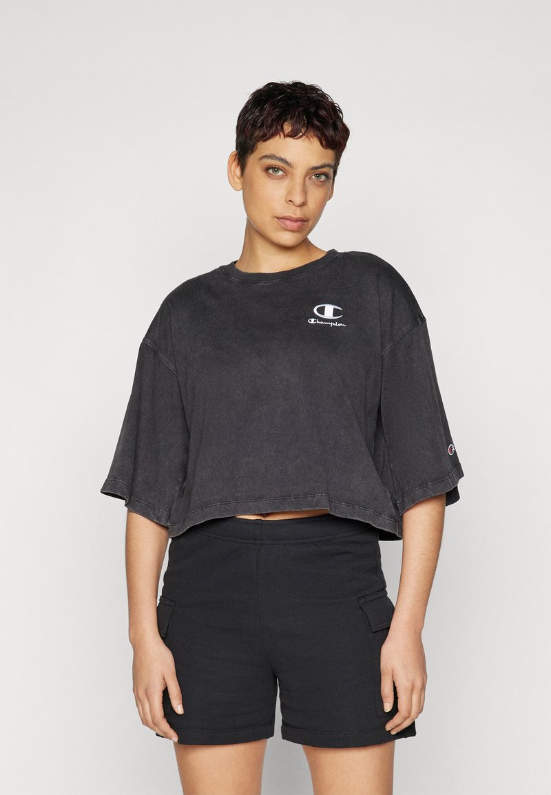 Tricou scurt negru, realizat dintr-un material moale, cu guler rotund și mâneci scurte. Include un logo Champion alb pe piept.
