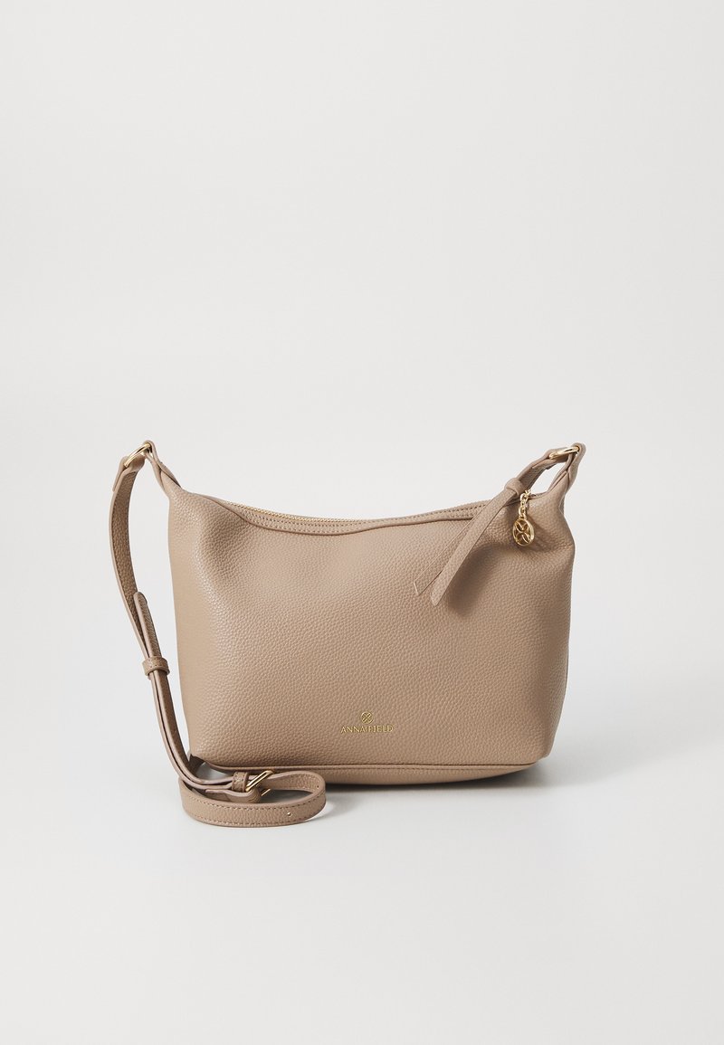 Bolso de cuero cruzado beige con un acabado texturizado, detalles en hardware dorado, cierre con cremallera y correa ajustable. Logo en la parte delantera.