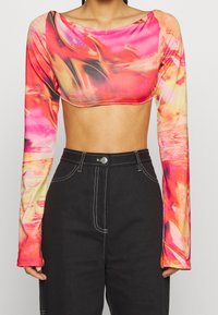 Langärmliges, cropped Oberteil in lebhaftem pink- und orangefarbenen abstrakten Muster, aus dehnbarem Stoff mit glatter Textur und weitem Ausschnitt.