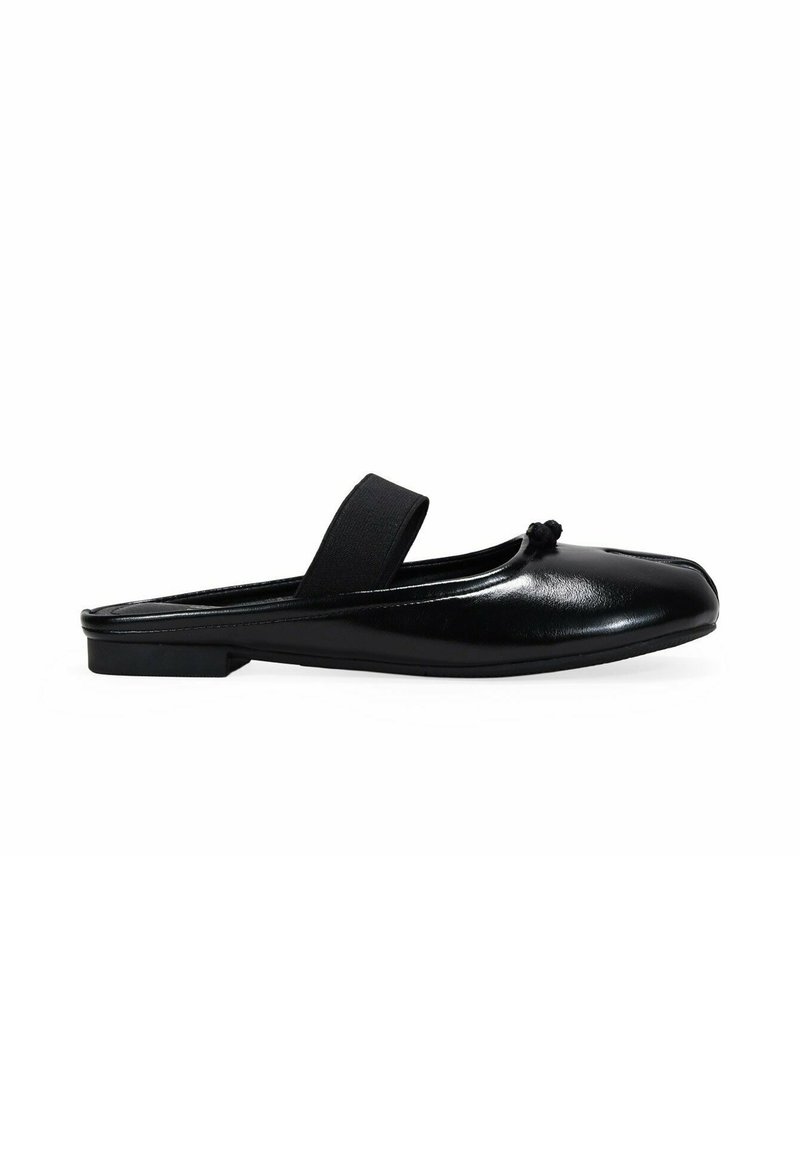 Zapato negro de cuero sin cordones con punta redondeada, banda elástica plana y un nudo decorativo en el frente. Textura suave y diseño minimalista.