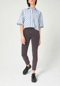 Lichtblauw gestreept cropped shirt met korte mouwen, gecombineerd met donkere grijze skinny jeans en zwarte platform schoenen.