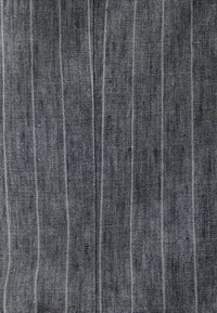 Tessuto scuro con sottili righe verticali in diverse tonalità di grigio, caratterizzato da una finitura strutturata e sottili variazioni nella trama.