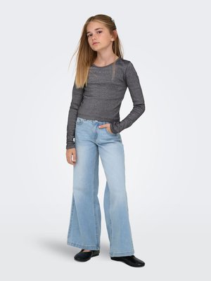 Grå, tætsiddende langærmet top kombineret med lyseblå bredbenede jeans og sorte sko. Kendetegnet ved en lige pasform og blød tekstur.