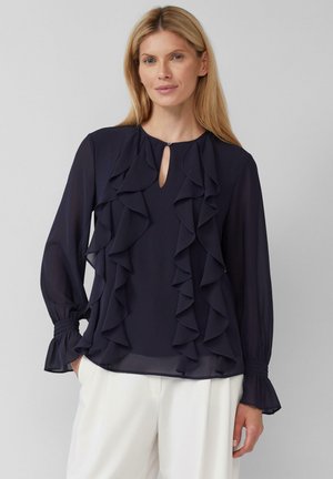 Blouse en chiffon bleu marine avec des détails froncés sur le devant et les manches, dotée d'un col en trou de serrure et de poignets élastiques.