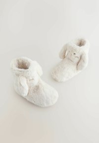 Botoșei pufoși, albi, cu o textură moale și vârf rotund, având accente cu urechi căzute și un interior confortabil, căptușit pentru căldură.