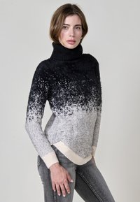 Črno-siv prelivajoč se pulover s turtleneck ovratnikom in puhasto teksturo; rebrasti manšeti in rob; prilegajoča zasnova, ki se zožuje v pasu.