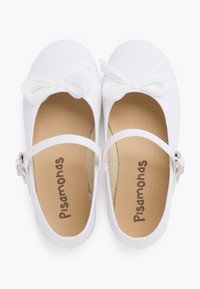 Scarpe in tessuto bianco con punta tonda, dotate di suola piatta e cinturino regolabile. Un fiocco decorativo bianco è posizionato davanti.