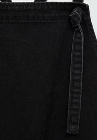 Zwarte denimstof met een gestructureerd oppervlak. Voorzien van een geknoopte band, zichtbare stiksels en een gestructureerd ontwerp.