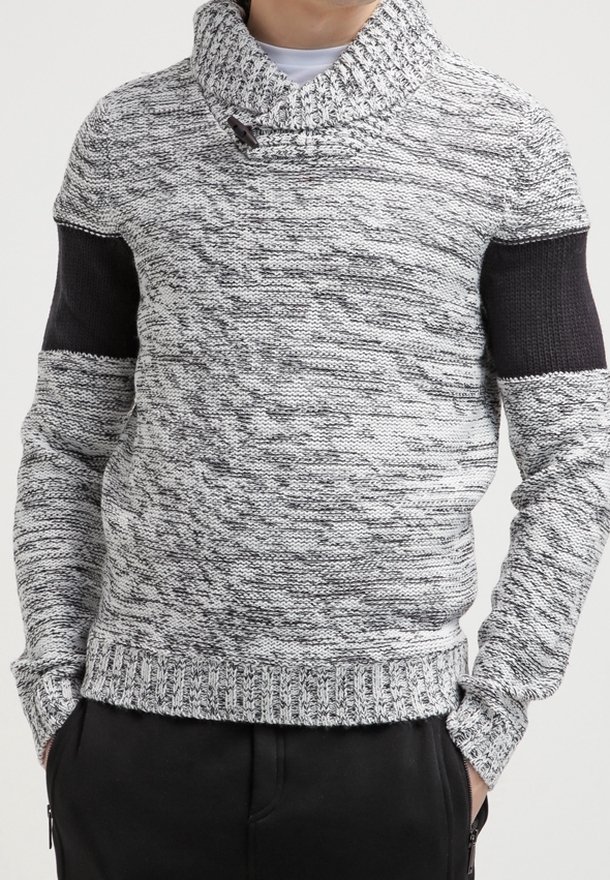 Grå och svart stickad tröja med krage, ribbad nederkant och strukturerad kropp. Har solida svarta detaljer på ärmarna.