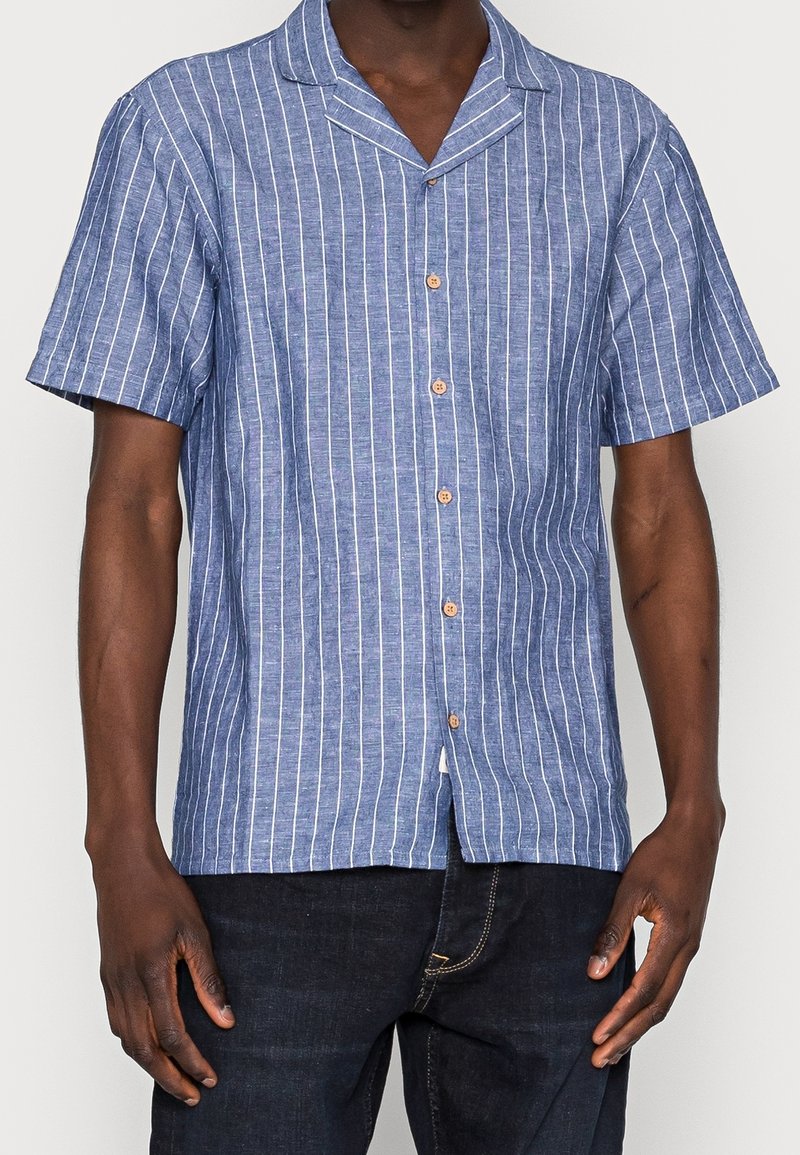 Korte mouw blouse in blauw met witte verticale strepen. Voorzien van een campkraag en houten knopen. Gestructureerde stof.
