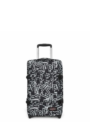 Valise à roulettes noire et blanche avec motif abstrait de lettres superposées et poignée télescopique déployée, logo Eastpak visible sur le devant.