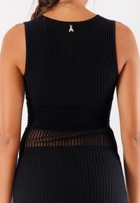 Abito nero a coste con silhouette aderente, pannello trasparente in vita e un piccolo logo dorato sul colletto posteriore.