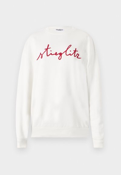White sweatshirt with long sleeves, featuring a prominent red cursive "stieglitz" logo on the front. Soft, textured fabric.
