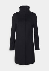 Mustassa, polvimittaisessa takissa on korkea kaulus, pitkät hihat ja suora leikkaus. Se on valmistettu sileästä kankaasta, jossa ei ole näkyviä kiinnityksiä tai koristeita.