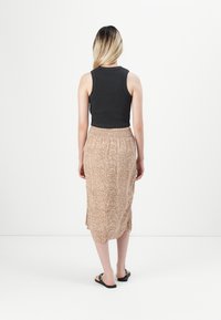 Top negro sin mangas combinado con una falda midi beige con estampado que presenta una cintura fruncida, tejido texturizado y aberturas laterales para mayor libertad de movimiento.