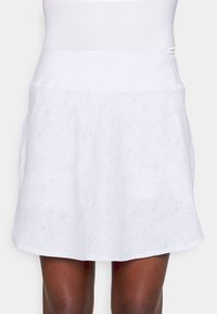 Falda blanca con un patrón texturizado de remolinos y flores. Cuenta con una cinturilla ancha y suave y un dobladillo acampanado con bolsillos laterales.
