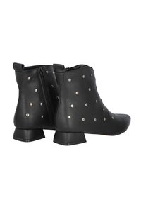 Botines negros de cuero, con tachuelas metálicas, cierre de cremallera en el lateral y tacón bajo apilado. Textura suave y punta afilada.