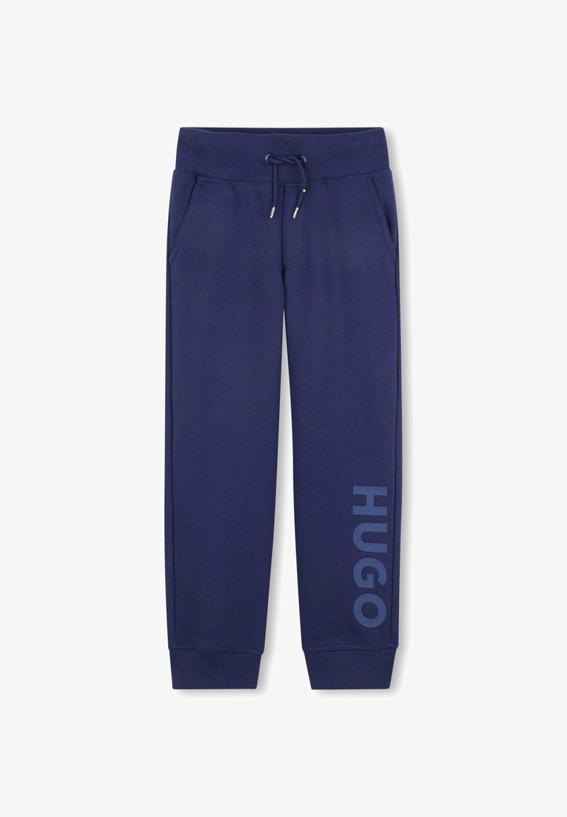 Navyblauwe trainingsbroek met een elastische tailleband, trekkoord, zijzakken en "HUGO" in grote letters gedrukt op het linkerpantalon.