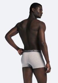 Boxer shorts en coton gris avec une taille noire "ALLSAINTS", design ajusté, montrant le dos et le bras droit d'un mannequin.