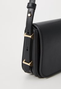 Black leather crossbody bag with a rectangular shape, featuring a gold-tone hardware accent on the adjustable strap and neat stitching.