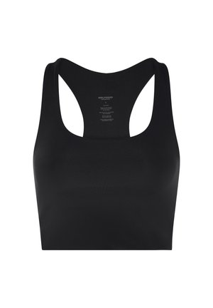 Nő fekete sportos ruházatban jógázik, tevapózt végez térdelve, háta homorú, egyik keze a lábán, karja felfelé nyújtva.