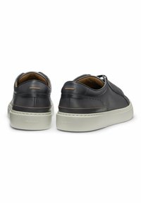 Black leather sneakers with a smooth finish, featuring a thick white rubber sole and subtle branding on the back. Minimalist design with clean lines.
