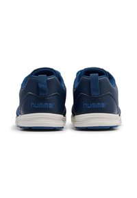Zapatillas deportivas azules con un acabado de cuero suave, suelas blancas y una lengüeta en el talón texturizada, que presentan el logo de "hummel" en azul.
