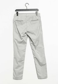 Ljusgrå byxor hängande på en svart galge med en slät yta, slim-fit design, två bakfickor och subtila sömnadsdetaljer.