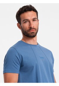 Modré bavlněné tričko s krátkým rukávem, kulatým výstřihem a kontrastním prošitím. Na přední straně vyšívané logo "Ombre".