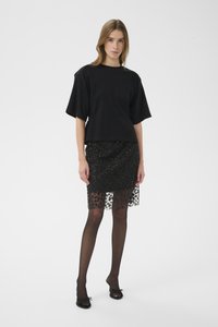 Zwart kort mouwen top gecombineerd met een zwarte pailletten rok met een kanten zoom. Model draagt doorschijnende zwarte panty's en zwarte open schoenen.