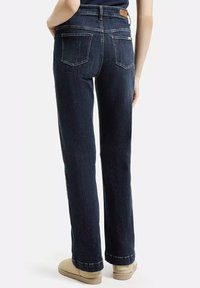 Ciemnoniebieskie dżinsy o prostym kroju, z pięcioma kieszeniami i małą skórzaną naszywką na tylnej części pasa. Miękka tekstura.