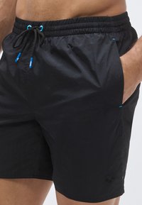 Μαύρα μαγιό σορτς κατασκευασμένα από ελαφρύ υλικό. Διαθέτουν ελαστική μέση με κορδόνι, πλαϊνές τσέπες και μπλε λεπτομέρειες.