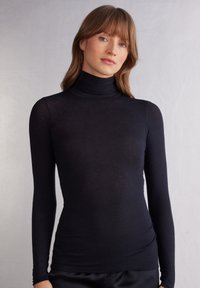 Zwarte lang-sleeve coltrui in een lichte, aansluitende pasvorm met een soepele textuur en hoge kraag, met een subtiele glans.
