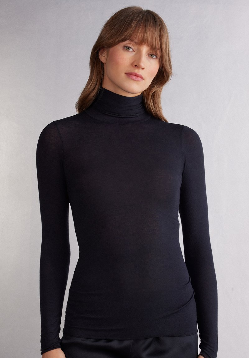 Zwarte lang-sleeve coltrui in een lichte, aansluitende pasvorm met een soepele textuur en hoge kraag, met een subtiele glans.