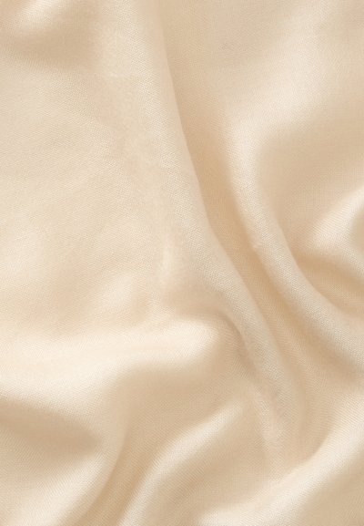 Tissu lisse de couleur crème avec des plis doux et une texture subtile, montrant des reflets lumineux à la surface du matériau.