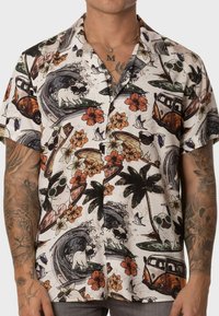 Camisa de manga corta de tejido ligero con patrones tropicales multicolores, que incluyen perros, flores y elementos de surf sobre un fondo blanco.