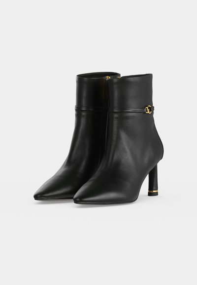 Botines de cuero negro con punteras puntiagudas, tacones altos y delgados, y pequeño detalle de hebilla dorada en el lateral.
