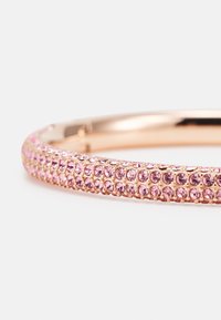 Náhrdelník v ružovom zlate zdobený malými ružovými kryštálmi, s hladkým, zakriveným tvarom a textúrovaným povrchom pre zvýšenie detailov.