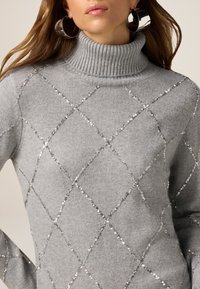 Szary sweter z golfem zdobiony diamentowymi wzorami z akcentami ze srebrnych cekinów, prezentujący miękką dzianinową fakturę i ściągaczowy kołnierz.