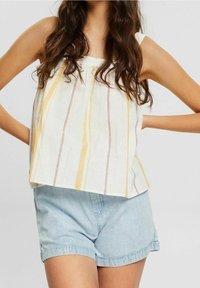 White linen top with yellow and maroon vertical stripes, paired with light blue denim shorts. Top features thin straps and a loose fit.