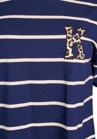 Minkštos medžiagos mėlynai dryžuotas marškinėlis. Su baltais horizontaliais dryžiais ir leopardų rašto laišku "K" ant krūtinės.