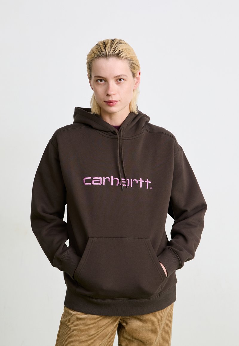 Bruine hooded sweatshirt met een roze "carhartt" logo, een voorste kangaroo zak, en ribgebreide mouwen met een zachte textuur.