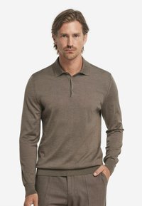 Braun langärmliges Polohemd aus weichem Material mit klassischem Kragen, Dreiknopfverschluss und gerippten Bündchen und Saum.